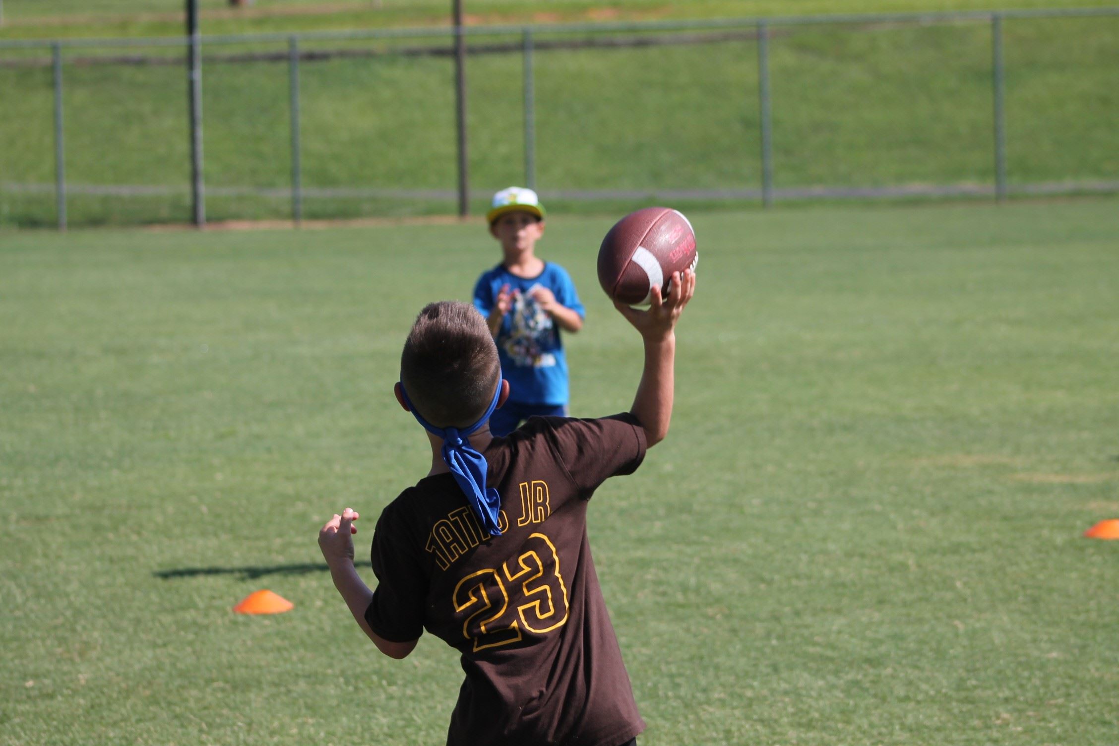 two children throwing football on field 
