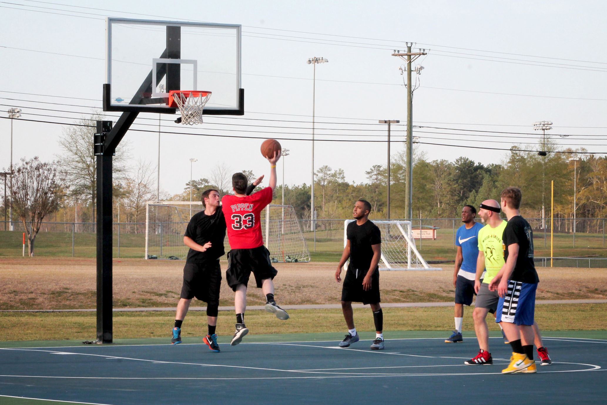 adults playing basketball on outdoor courts located at Herman C Michael Park